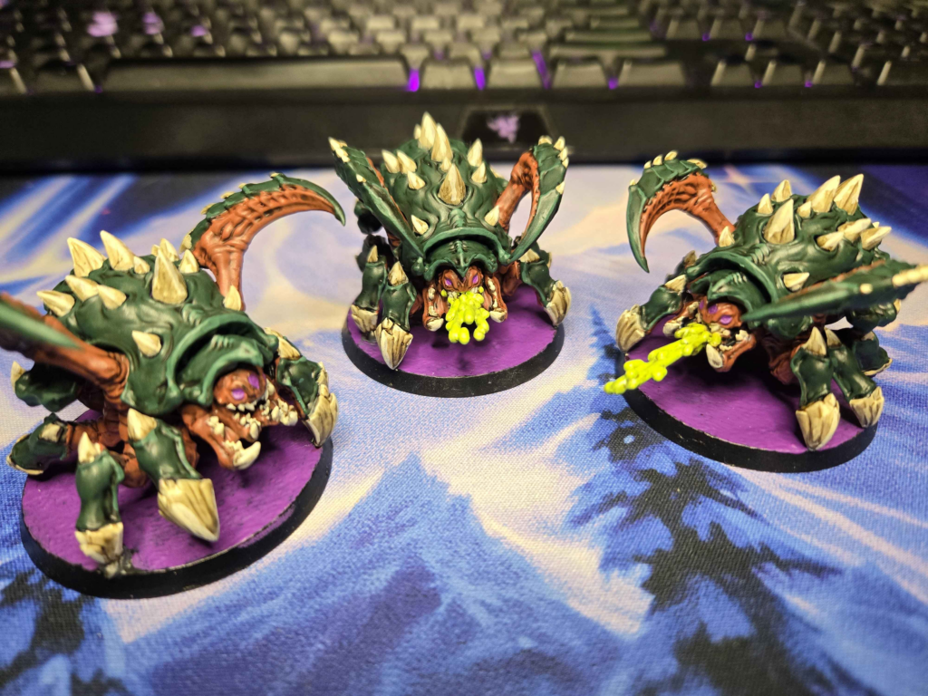 StarCraft TMG - bemalte Zerg-Roaches in Gruen und Orange auf lila Bases, Community-Malarbeit von Reddit-Nutzer Szadkill (Quelle: https://www.reddit.com/r/StarCraftTMG/comments/1worgdd/unit_of_roaches_done/)